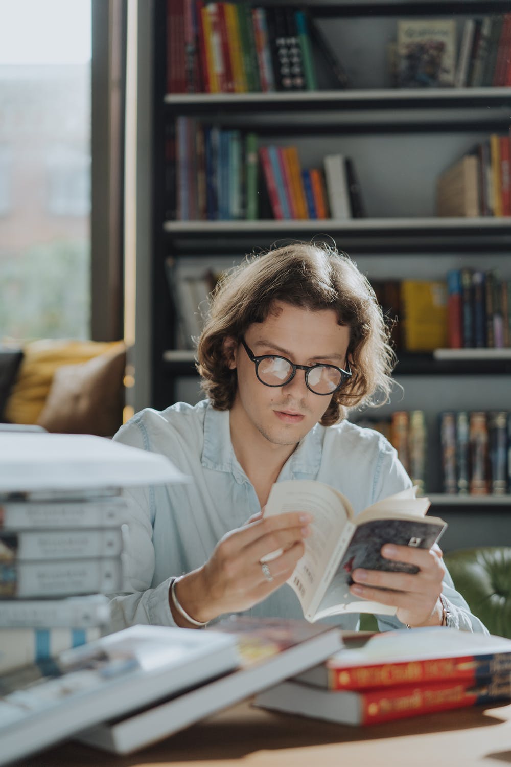 Hombre joven en su despacho con libreria investigando un asunto de crucial importancia