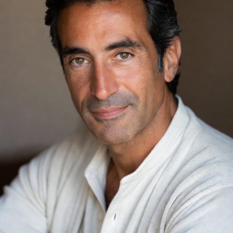 Hombre moreno de mediana edad, con camisa blanca y de rasgos mediterráneos que mira con serenidad a la cámara.